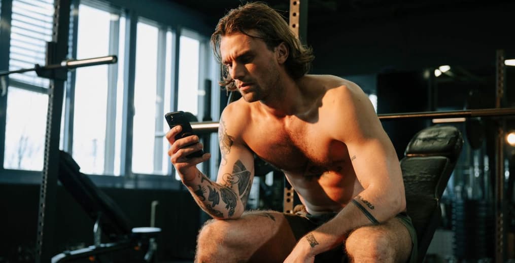 An athlete in workout gear casually scrolling through their phone, conveying a relaxed moment of browsing.
