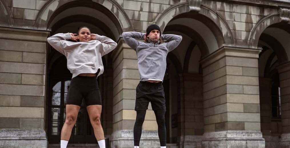 A man and woman performing burpees outside in cold weather, staying active during the holiday season.