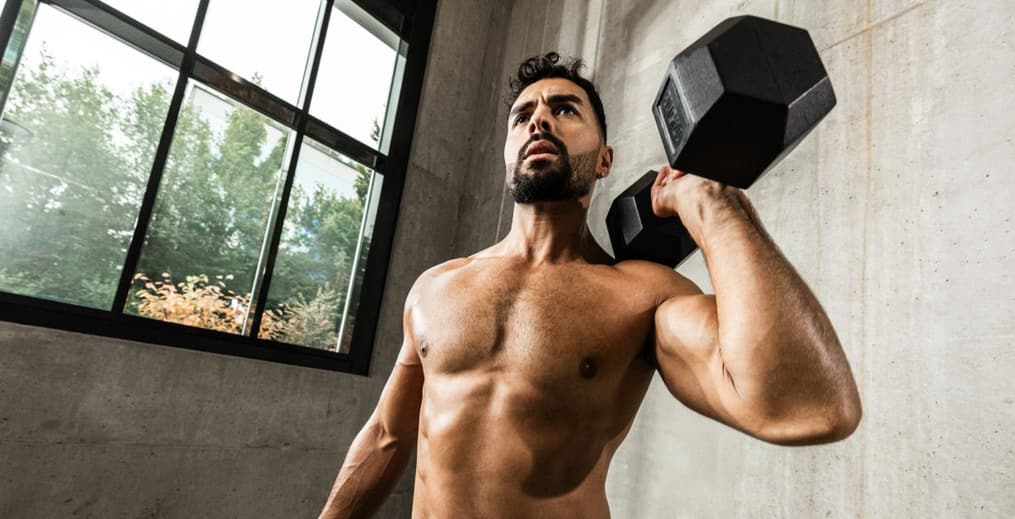 Athlete performing a dumbbell shoulder press to build strong, healthy shoulders