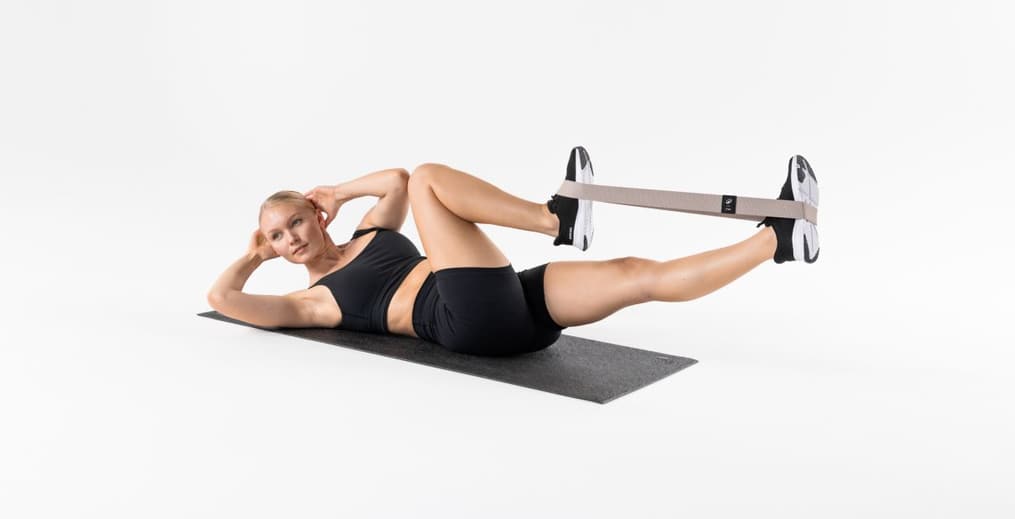 Athlete performing Bicycle Crunches with a glute band for core and hip activation