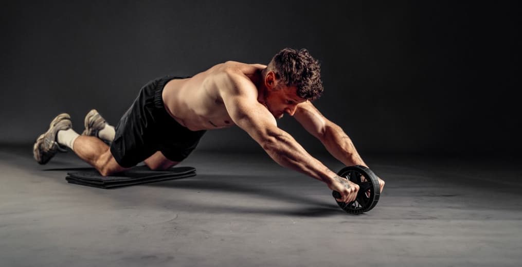 Athlete performing an ab wheel rollout to strengthen the core and improve stability.