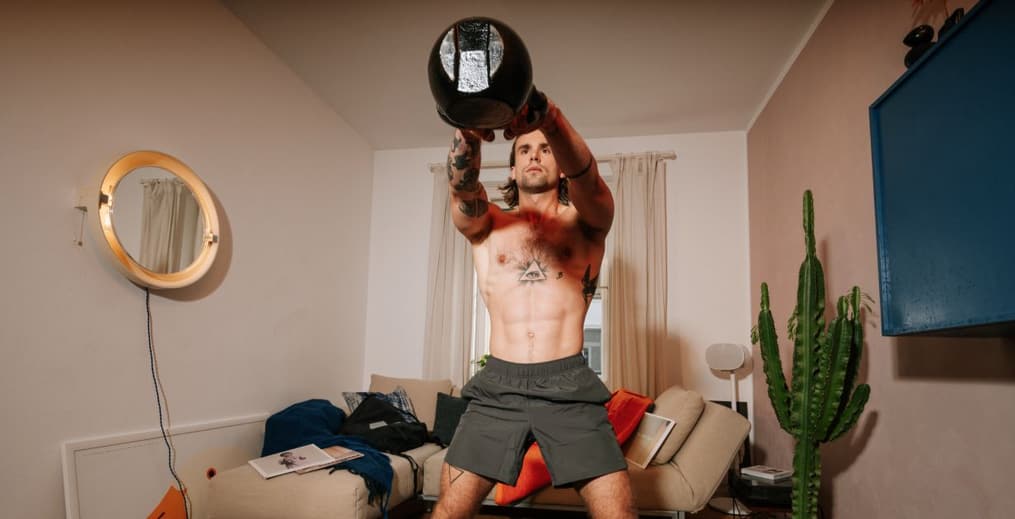 Athlete performing kettlebell swings at home to build strength and endurance.