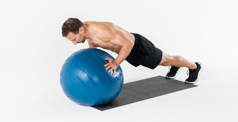 Athlete performing pushups with hands on a gym ball to improve core and upper body stability.