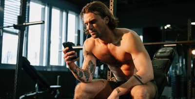 An athlete in workout gear casually scrolling through their phone, conveying a relaxed moment of browsing.
