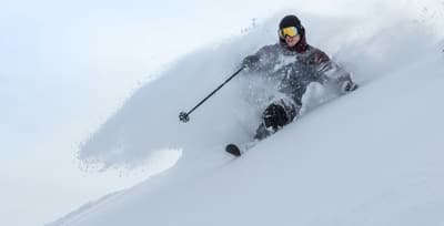 An athlete skiing downhill through powder snow, showcasing speed, control, and winter sports excitement.