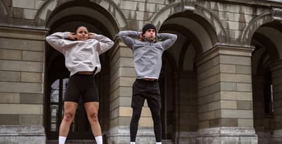 A man and woman performing burpees outside in cold weather, staying active during the holiday season.