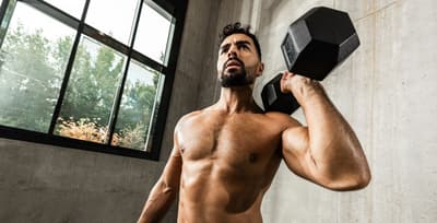 Athlete performing a dumbbell shoulder press to build strong, healthy shoulders