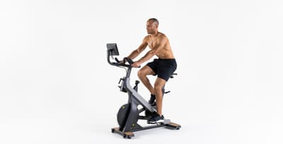 A man using an indoor smart bike to track his power and heart rate during a training session.