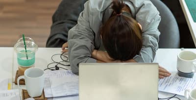 Stressed person with head on a cluttered desk