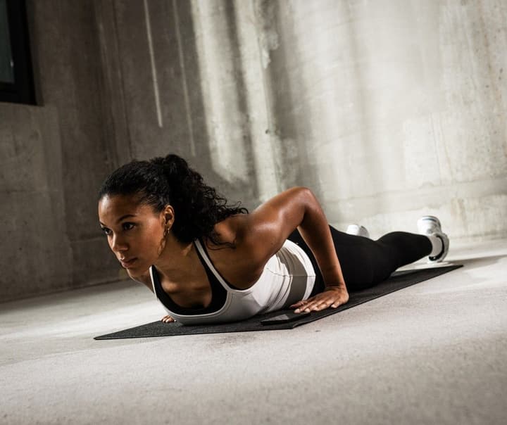 Woman at the bottom of a Pushup on a training mat