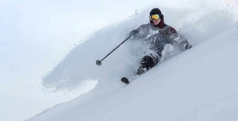An athlete skiing downhill through powder snow, showcasing speed, control, and winter sports excitement.