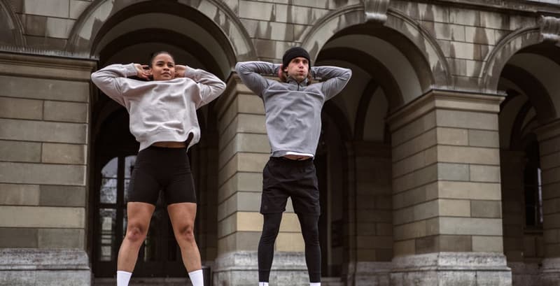 A man and woman performing burpees outside in cold weather, staying active during the holiday season.