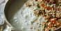 Bowl of creamy Greek yogurt topped with dried fruit and nuts on a table
